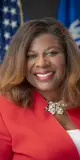 Official portrait of State Senator LaTonya Johnson, a Wisconsin Democrat, smiling warmly. She is wearing a bright red dress and standing in front of the Wisconsin state flag. Her hair is styled in loose waves, and the portrait highlights her commitment to public service and leadership in the state legislature.