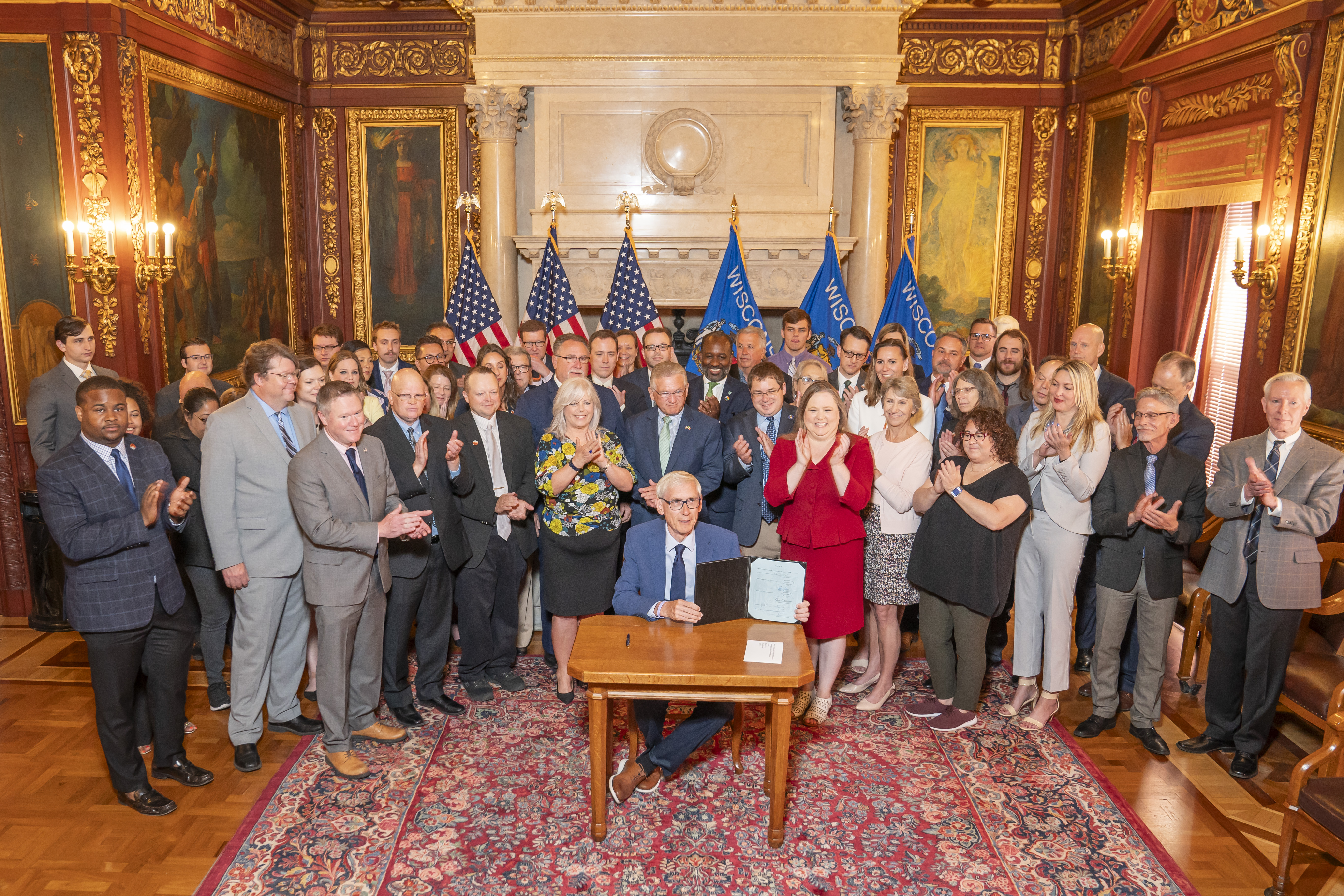 Sen. Spreitzer and other legislators clap as Governor Tony Evers signs a housing bill into state law.