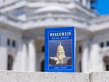 A Wisconsin Blue Book is pictured in front of the State Capitol. 