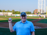 Sen. Spreitzer smiles with a baseball after throwing the first pitch at a Beloit Sky Carp game. 