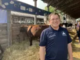 Sen. Spreitzer stands in front of a cow at the Green County Fair. 