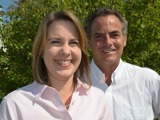 State Representative Dianne Hesselbein poses with State Senator John Erpenbach for a photo. She is a white woman with medium brown hair and he is a white man with dark hair. They are both wearing light-colored collared shirts and are outside somewhere sunny.