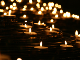 Stock photo of a collection of small candles, likely meant to honor lives lost in a tragedy.