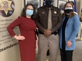 State Representatives Dianne Hesselbein and Melissa Sargent pose for a photo wiht Dane County Sheriff Barrett. Rep Sargent is a white woman with dark hair wearing a red dress. Rep. Hesselbein is a white woman with medium brown hair wearing a blue jacket. Sheriff Barrrett is a Black man wearing his uniform and badge. They are all wearing facemasks to protect themselves from the COVID-19 pandemic.