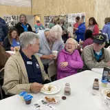 Constituents laugh alongside Senator Smith while enjoying breakfast at the Pepin County Dairy Breakfast in 2024.