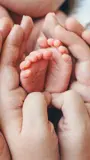 Infants feet held by the parents hands.