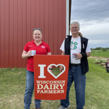 Senator Smith and Representative Jodi Emerson at the Eau Claire Dairy Breakfast holding a sign that says "I heart Wisconsin Dairy Farmers"