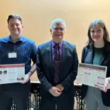 Senator Smith posing with two students presenting research at UW-River Falls' Research in the Rotunda Day.