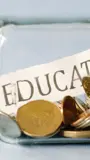 Jar on its side filled with coins and a slip of paper with education written on it.