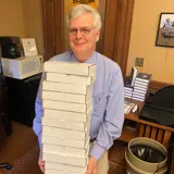 Senator Smith holding a stack of blue books in his office ready to be mailed to constituents.