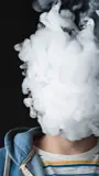 Person exhaling smoke in a large puff that covers their face.