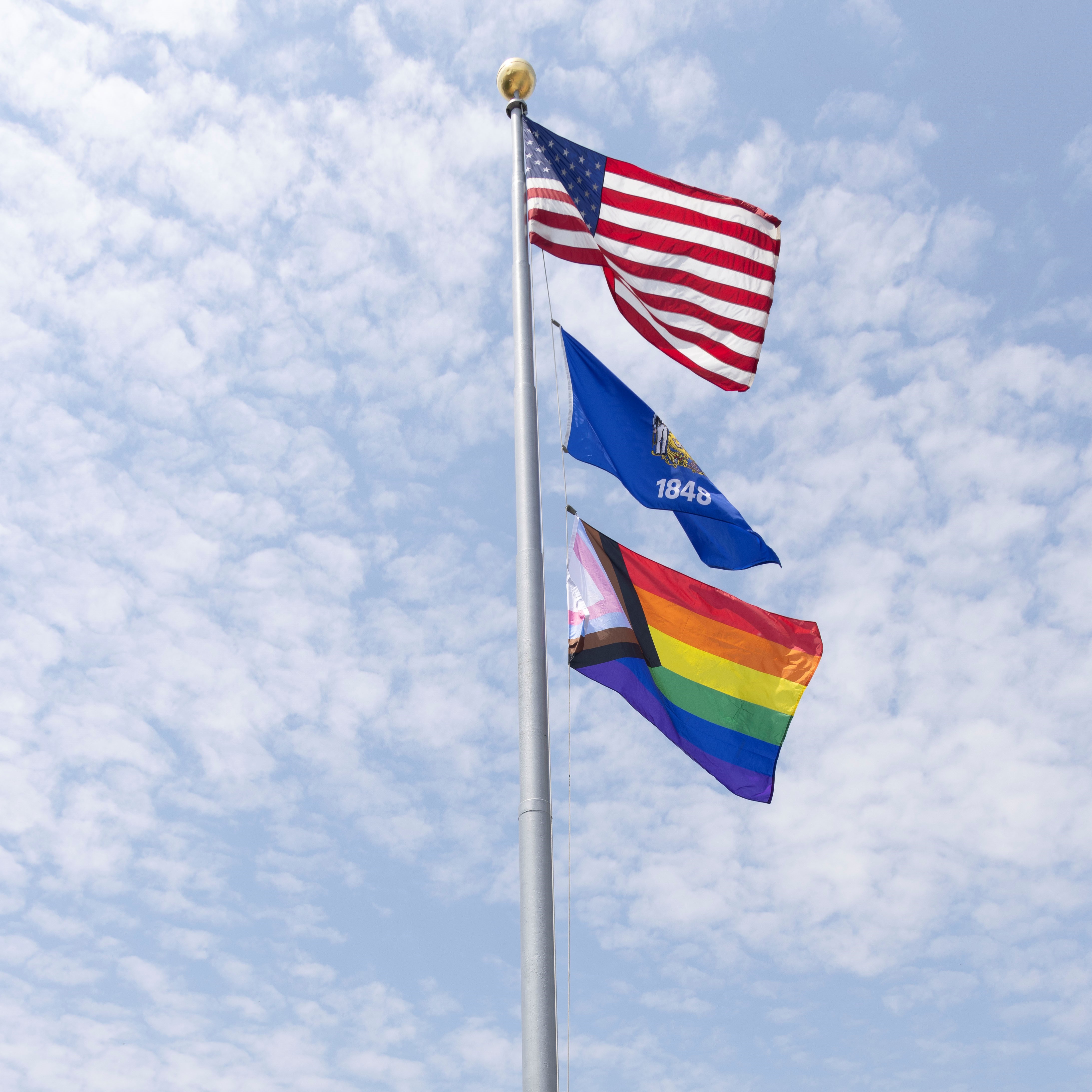 The American flag, the Wisconsin state flag and the Progress Pride flag fly over the Wisconsin state capitol.