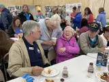 Constituents laugh alongside Senator Smith while enjoying breakfast at the Pepin County Dairy Breakfast in 2024.