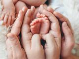 Infants feet held by the parents hands.