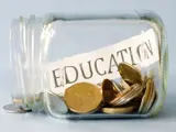 Jar on its side filled with coins and a slip of paper with education written on it.