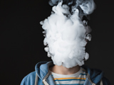 Person exhaling smoke in a large puff that covers their face.